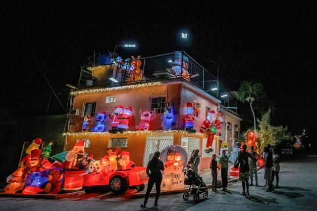 Residents gather around a house powered by a generator and decorated with Santa Claus inflatables to celebrate Christmas amid a blackout in Havana on December 25, 2025. (Photo by Adalberto ROQUE / AFP)