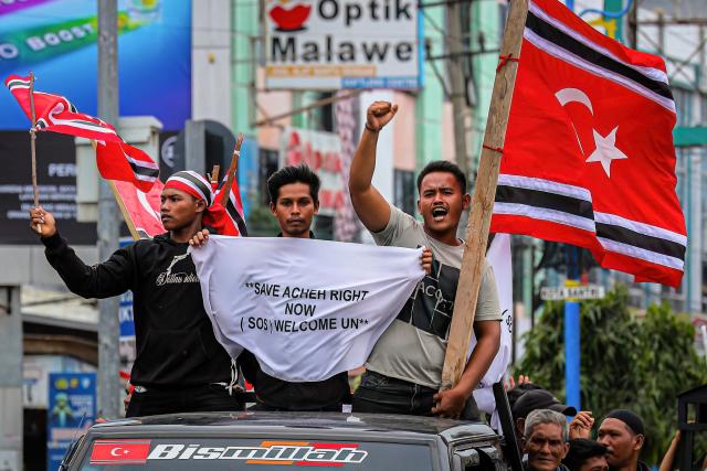People hold Free Aceh Movement (GAM) flags while escorting humanitarian aid, meant for survivors of the recent devastating floods in Sumatra, in Bireuen, Aceh Province on December 25, 2025. Despite the efforts by the Indonesian government, frustration is mounting over sluggish relief efforts which has fuelled demands on Jakarta to declare a national disaster and permit international assistance into affected areas. The provincial government in Aceh said it had already turned to several United Nations agencies for help, citing their previous aid campaigns in the wake of the 2004 tsunami. (Photo by AMANDA JUFRIAN / AFP)