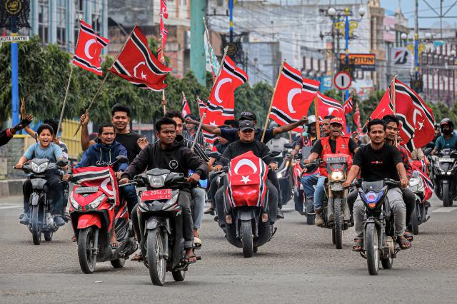 People hold Free Aceh Movement (GAM) flags while escorting humanitarian aid, meant for survivors of the recent devastating floods in Sumatra, in Bireuen, Aceh Province on December 25, 2025. Despite the efforts by the Indonesian government, frustration is mounting over sluggish relief efforts which has fuelled demands on Jakarta to declare a national disaster and permit international assistance into affected areas. The provincial government in Aceh said it had already turned to several United Nations agencies for help, citing their previous aid campaigns in the wake of the 2004 tsunami. (Photo by AMANDA JUFRIAN / AFP)