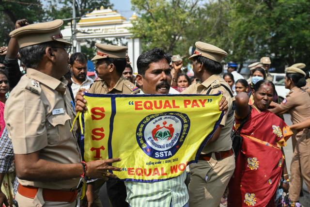 Police personnel detain a teacher during a protest demanding salary hikes and regularization of government jobs in Chennai on December 26, 2025. (Photo by R.Satish BABU / AFP)