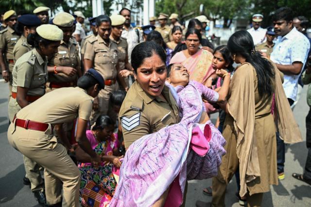 A police personnel carries a teacher who fainted during a protest demanding salary hikes and regularization of government jobs in Chennai on December 26, 2025. (Photo by R.Satish BABU / AFP)