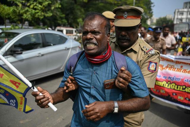 A police personnel detains a teacher during a protest demanding salary hikes and regularization of government jobs in Chennai on December 26, 2025. (Photo by R.Satish BABU / AFP)