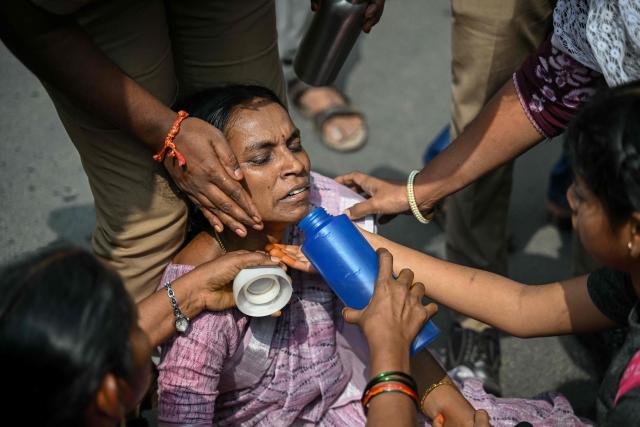 TOPSHOT - A teacher is being attended by people after she fainted during a protest demanding salary hikes and regularization of government jobs in Chennai on December 26, 2025. (Photo by R.Satish BABU / AFP)