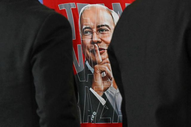 This picture shows a supporter's t-shirt bearing an image of Malaysia's former prime minister Najib Razak hushing, during his 1MDB trial at the Palace of Justice, which houses the Malaysian Court of Appeal and Federal Court, in Putrajaya on December 26, 2025, ahead of the verdict. (Photo by Mohd RASFAN / AFP)