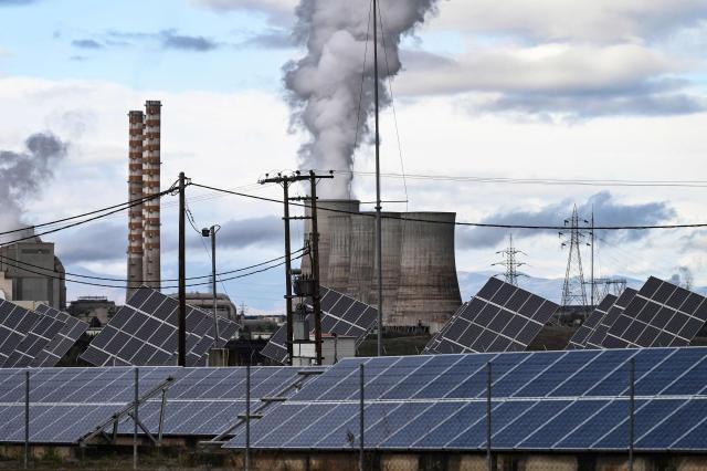 This photograph shows the Agios Dimitrios Power Station, a lignite-fired power plant next to solar panels in Agios Dimitros, near Kozani, in north-western Greece on November 20, 2025. As part of an environmental drive that became known as the European Union Green Deal, Greece in 2019 decided to drastically cut back on the use of lignite in electricity production. Despite decades of air and water pollution that have verifiably caused cancer and other ailments, the residents of Agios Dimitrios village will be sorry to see the Public Power Corporation plant -- a source of employment for many -- decommissioned. The Agios Dimitrios plant, just a few hundred metres from the village, is scheduled to shut in May 2026. (Photo by Sakis Mitrolidis / AFP)