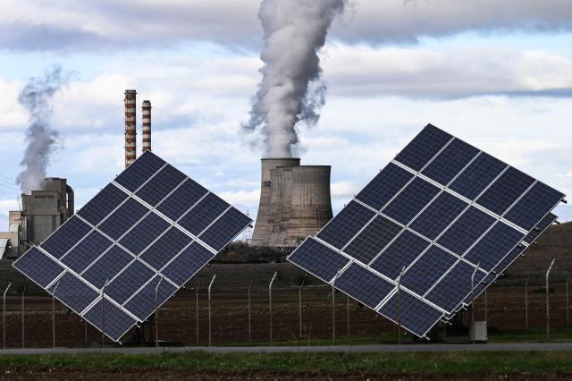 This photograph shows the Agios Dimitrios Power Station, a lignite-fired power plant next to solar panels in Agios Dimitros, near Kozani, northwestern Greece on November 20, 2025. As part of an environmental drive that became known as the European Union Green Deal, Greece in 2019 decided to drastically cut back on the use of lignite in electricity production. Despite decades of air and water pollution that have verifiably caused cancer and other ailments, the residents of Agios Dimitrios village will be sorry to see the Public Power Corporation plant -- a source of employment for many -- decommissioned. The Agios Dimitrios plant, just a few hundred metres from the village, is scheduled to shut in May 2026. (Photo by Sakis Mitrolidis / AFP)