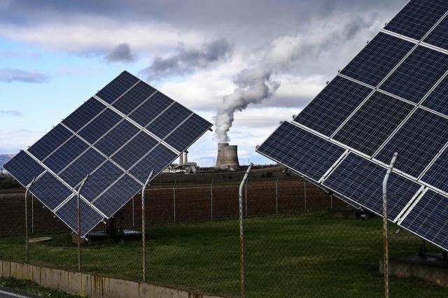 This photograph shows the Agios Dimitrios Power Station, a lignite-fired power plant next to solar panels in Agios Dimitros, near Kozani, northwestern Greece on November 20, 2025. As part of an environmental drive that became known as the European Union Green Deal, Greece in 2019 decided to drastically cut back on the use of lignite in electricity production. Despite decades of air and water pollution that have verifiably caused cancer and other ailments, the residents of Agios Dimitrios village will be sorry to see the Public Power Corporation plant -- a source of employment for many -- decommissioned. The Agios Dimitrios plant, just a few hundred metres from the village, is scheduled to shut in May 2026. (Photo by Sakis Mitrolidis / AFP)