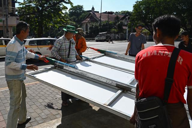 Members of Union Solidarity and Development Party (USDP) remove their signboard on the final day of the campaign ahead of the start of Myanmar's general election in Yangon on December 26, 2025. Myanmar's junta will preside over elections starting on December 28, advertising the vote as a return to democratic normality five years after staging a coup that triggered civil war. (Photo by Sai Aung MAIN / AFP)