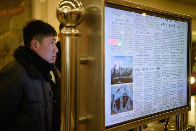 (FILES) A man reads North Korea's Rodong Sinmun newspaper, which includes an article (centre, 2nd from bottom) on the inauguration of US President Donald Trump, on a digital monitor displayed in the Kaeson Station of the Pyongyang Metro in Pyongyang on January 22, 2025. South Korea said on December 26 it will reclassify North Korea's long-banned state newspaper as general information, easing public access, in the latest overture from the administration of dovish President Lee Jae Myung. Seoul's government convened on December 26 an inter-agency meeting and confirmed a consensus among the relevant parties regarding the "reclassification of the Rodong Sinmun newspaper from special material to general material", it said in a statement. (Photo by KIM Won Jin / AFP)
