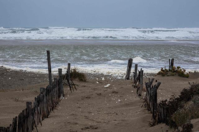 This photograph shows waves of the Mediterranean Sea overflowing on the dunes of a beach at Canet en Roussillon in the Pyrenees-Orientales department in the south-west of France on December 26, 2025. Currently under a Meteo France alert, the Pyrenees Orientales are experiencing flooding and rainfall of more than 200mm per hour across the department. (Photo by Jean-Christophe MILHET / AFP)