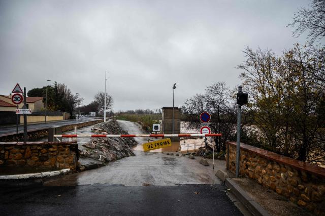 This photograph shows a flooded road with a closed barrier in Rivesaltes in the Pyrenees-Orientales department, south-western France, on December 26, 2025. Currently under a Meteo France alert, the Pyrenees Orientales are experiencing flooding and rainfall of more than 200mm per hour across the department. (Photo by Jean-Christophe MILHET / AFP)
