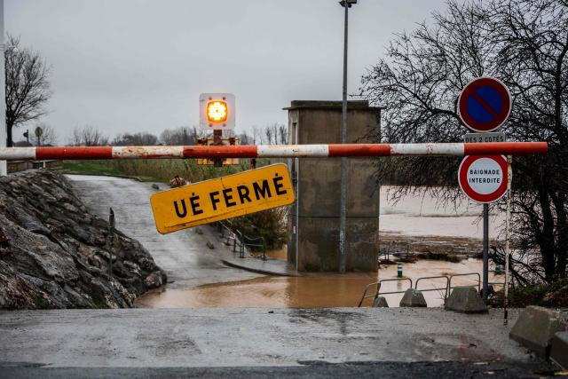 This photograph shows a flooded road with a closed barrier in Rivesaltes in the Pyrenees-Orientales department, south-western France, on December 26, 2025. Currently under a Meteo France alert, the Pyrenees Orientales are experiencing flooding and rainfall of more than 200mm per hour across the department. (Photo by Jean-Christophe MILHET / AFP)