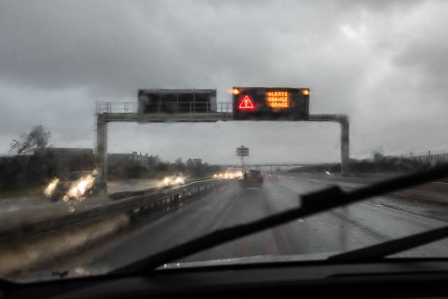 This photograph taken from inside a car shows a road sign reading "Orange Alert Storm" as  rain pours on a highway near Perpignan in the Pyrenees-Orientales department, south-western France, on December 26, 2025. Currently under a Meteo France alert, the Pyrenees Orientales are experiencing flooding and rainfall of more than 200mm per hour across the department. (Photo by Jean-Christophe MILHET / AFP)