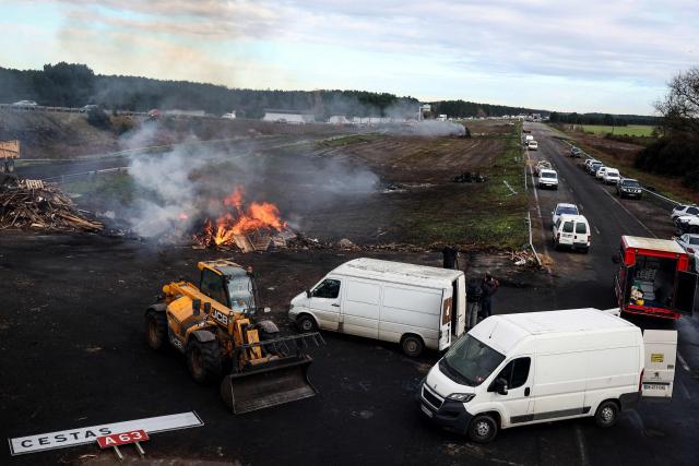 A photograph taken on December 26, 2025 shows wood and hay set on fire and tractors blocking the A63 highway in Cestas south-western France, during a farmers demonstration to protest against the government's mandatory culling protocol for cattle herds affected by lumpy skin disease (dermatose nodulaire contagieuse).  (Photo by ROMAIN PERROCHEAU / AFP)