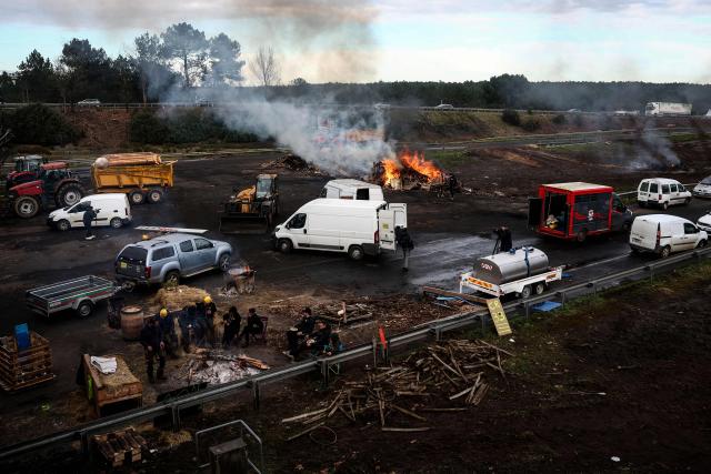 A photograph taken on December 26, 2025 shows wood and hay set on fire and tractors blocking the A63 highway in Cestas south-western France, during a farmers demonstration to protest against the government's mandatory culling protocol for cattle herds affected by lumpy skin disease (dermatose nodulaire contagieuse).  (Photo by ROMAIN PERROCHEAU / AFP)