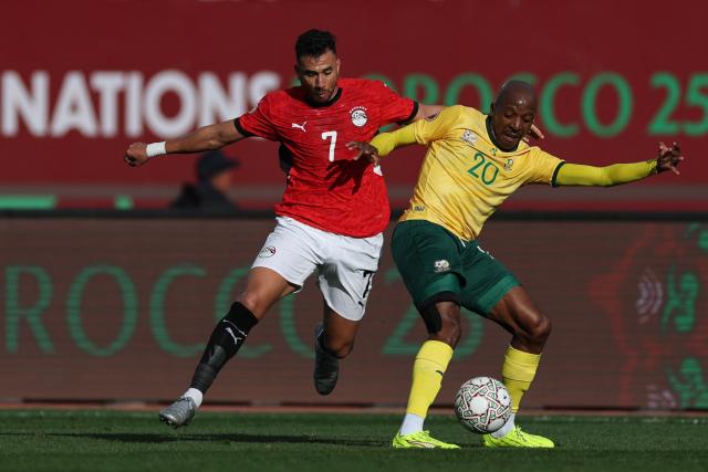 Egypt's forward #7 Mahmoud Trezeguet challenges South Africa's defender #20 Khuliso Mudau  during the Africa Cup of Nations (CAN) Group B football match between Egypt and South Africa at Adrar Stadium in Agadir on December 26, 2025. (Photo by FRANCK FIFE / AFP)