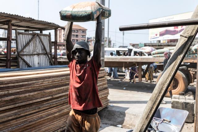 A worker carries a bag full of cement to a nearby warehouse in the neighborhood of Cosa in Conakry, on December 26, 2025, ahead of Guinea’s Presidential election on December 28, 2025. (Photo by PATRICK MEINHARDT / AFP)