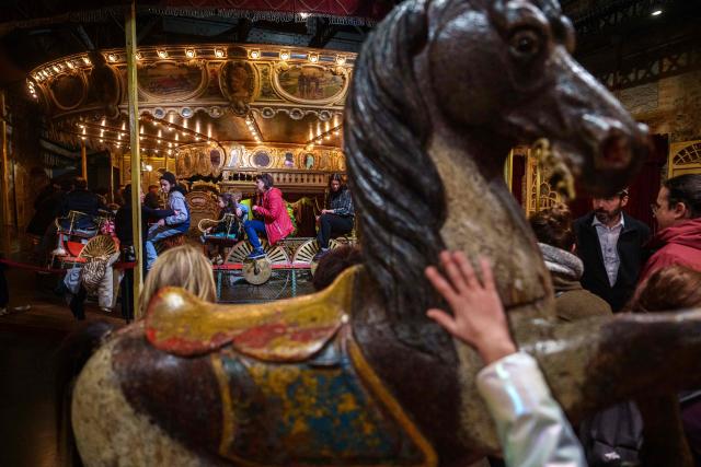 TOPSHOT - People ride a vintage carousel during the annual Festival du Merveilleux at the Musee des Arts Forains in Paris on December 26, 2025. (Photo by Dimitar DILKOFF / AFP)