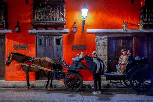 (FILES) A couple sits in a horse-drawn carriage while touring the historic center of Cartagena, Colombia, on March 07, 2025. Traditional horse-drawn carriages will be banned starting December 29, 2025, in Cartagena, a tourist jewel of Colombia, the local mayor announced on December 26. (Photo by Manuel PEDRAZA / AFP)