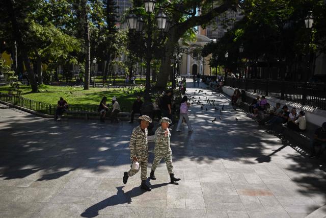 Two members of the Bolivarian National Militia walk through Bolivar Square in downtown Caracas on December 26, 2025. (Photo by Federico PARRA / AFP)