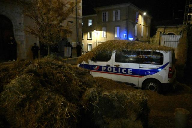 A Police van is covered in hay as Farmers from the "Coordination Rurale" (CR32) dump hay in front of the Gers prefecture building in protest against the French government's mandatory culling protocol for cattle herds affected by lumpy skin disease (dermatose nodulaire contagieuse), in Auch, southwestern France, on December 26, 2025. (Photo by Matthieu RONDEL / AFP)