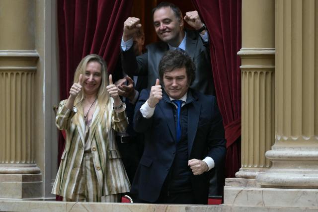 (FILES) Argentinas President Javier Milei (R) and the Secretary General of the Presidency Karina Milei give the tnbs up as the Chief of Cabinet and government spokesman Manuel Adorni raises his clenched fists during the oath ceremony at the Chamber of Deputies of the Argentine Congress in Buenos Aires on December 3, 2025. On December 26, 2025, the Argentine Senate approved Javier Milei's first budget proposal, which had previously received approval from deputies, providing a boost for the second half of his term after two years of governing with outdated figures. (Photo by JUAN MABROMATA / AFP)