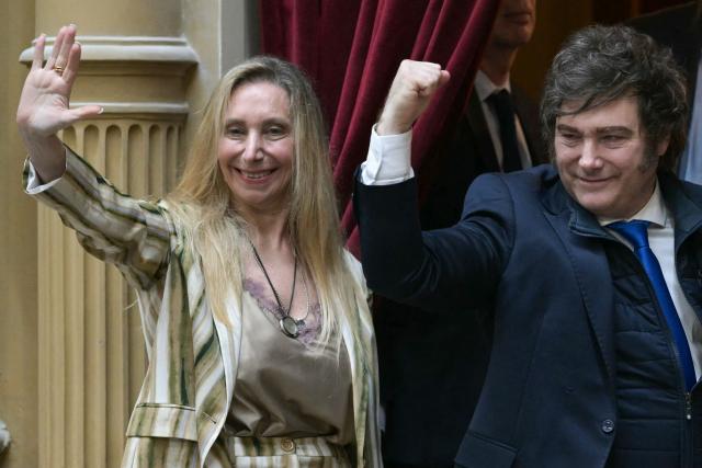 (FILES) Argentina’s President Javier Milei (R) raises his clenched fist as the Secretary General of the Presidency Karina Milei waves during the oath ceremony at the Chamber of Deputies of the Argentine Congress in Buenos Aires on December 3, 2025. On December 26, 2025, the Argentine Senate approved Javier Milei's first budget proposal, which had previously received approval from deputies, providing a boost for the second half of his term after two years of governing with outdated figures. (Photo by JUAN MABROMATA / AFP)
