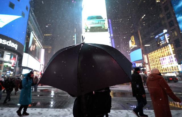 People enjoy the snowfall in Times Square on December 26, 2025, in New York City. New York, the US largest city, was bracing for up to 10 inches (25 centimeters) of snow overnight, the most in four years. (Photo by TIMOTHY A. CLARY / AFP)