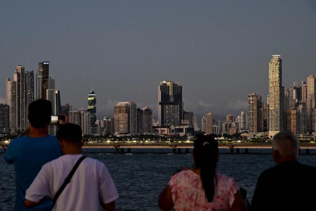 Tourists take photos of the skyline from Panama City's old town on December 26, 2025. (Photo by MARTIN BERNETTI / AFP)