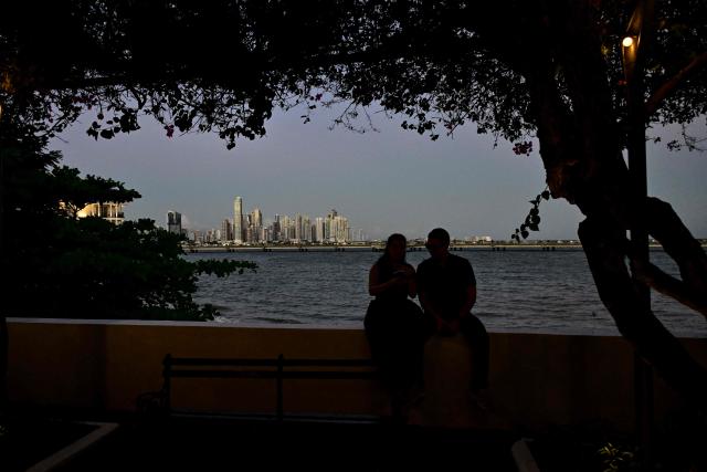 A couple looks at the skyline of Panama City on December 26, 2025. (Photo by MARTIN BERNETTI / AFP)