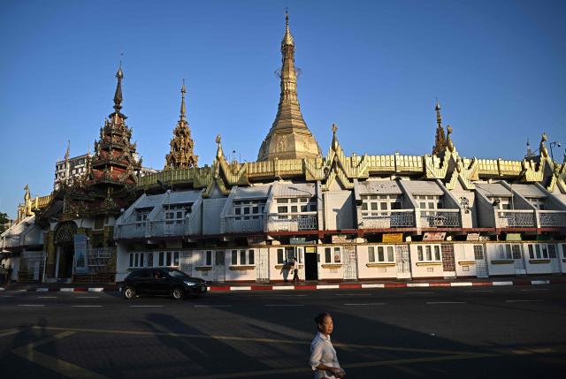 TOPSHOT - A woman walks past the Sule Pagoda in Yangon on December 27, 2025, a day before the start of Myanmar's general election. (Photo by Lillian SUWANRUMPHA / AFP)