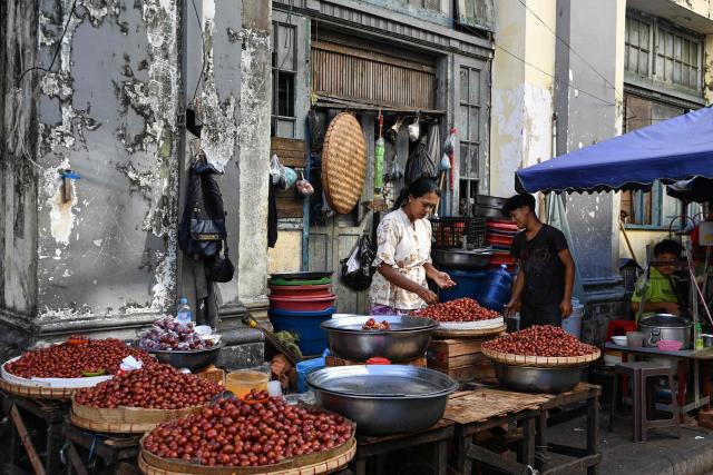 A street vendor is seen at a street market in Yangon on December 27, 2025, a day before the start of Myanmar's general election. (Photo by NHAC NGUYEN / AFP)