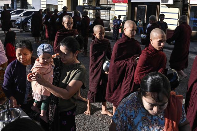 TOPSHOT - People give alms to Buddhist monks in Yangon on December 27, 2025, a day before the start of Myanmar's general election. (Photo by Lillian SUWANRUMPHA / AFP)