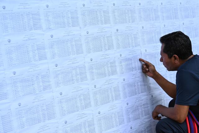 TOPSHOT - A man checks name lists at a polling station a day before the start of Myanmar's general election in Yangon on December 27, 2025. (Photo by NHAC NGUYEN / AFP)