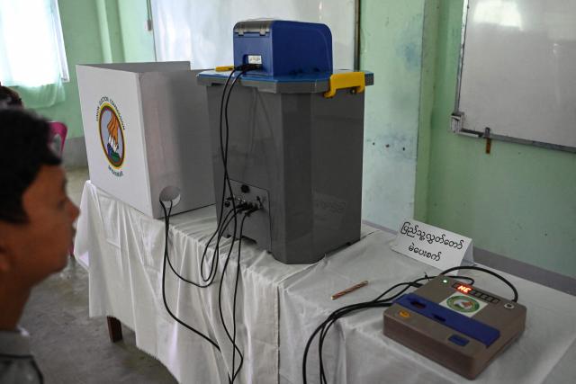 A member of Myanmar's Union Election Commission (UEC) prepares a voting station a day before the start of Myanmar's general election in Yangon on December 27, 2025. (Photo by NHAC NGUYEN / AFP)