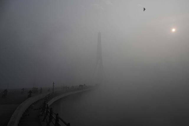 TOPSHOT - Commuters ride along the Signature Bridge over Yamuna river amid dense smog in New Delhi on December 27, 2025. (Photo by Arun SANKAR / AFP)