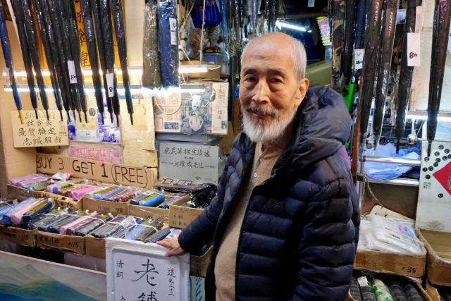 Yau Yiu-wai, 73, one of the few remaining umbrella repairmen in Hong Kong, poses poses for a photo in Hong Kong’s Sham Shui Po district on December 26, 2025. Scores of residents flocked to a cramped shop in Hong Kong's old district to bid farewell to the city's "king of umbrellas", who is retiring after spending decades repairing umbrellas at his family business. (Photo by Tommy WANG / AFP) / To go with 'HONG KONG-CHINA-SOCIAL, REPORTAGE' by Tommy Wang