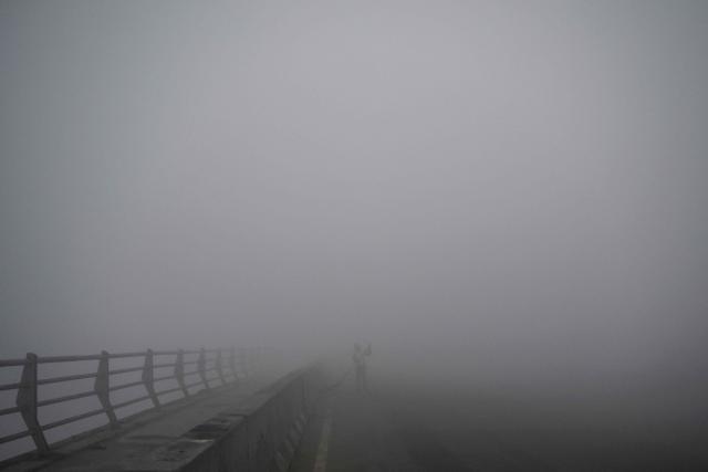 A worker sweeps a street amid dense smog in New Delhi on December 27, 2025. (Photo by Arun SANKAR / AFP)