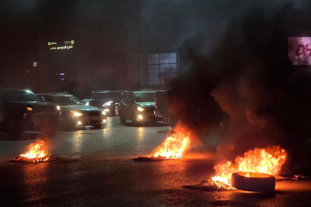 Traffic is partially blocked by burning tires as protesters block a key intersection of the capital with calls to bring down the government, in the Libyan capital Tripoli late on December 26, 2025. (Photo by Mahmud TURKIA / AFP)