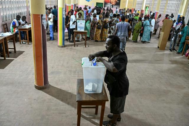 A voter casts his ballot at a polling station in Abidjan on December 27, 2025 during Ivory Coast's legislative elections. (Photo by SIA KAMBOU / AFP)
