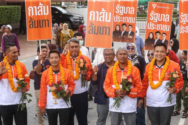 Members of People's Party (PP) hold placards as they gather on the first day of the registration for Thailand's upcoming general election in the southern province of Pattani on December 27, 2025. (Photo by Tuwaedaniya MERINGING / AFP)