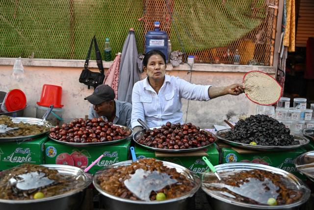 Street vendors wait for customers at a market in Yangon on December 27, 2025, a day before the start of Myanmar's general election. (Photo by NHAC NGUYEN / AFP)