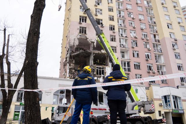 Ukrainian rescuers stand in front of a damaged residential building following Russian drones and missiles attack, in Kyiv, on December 27, 2025, amid the Russian invasion in Ukraine. Several powerful explosions rocked Kyiv on December 27, 2025 as authorities warned that the Ukrainian capital was under threat of missile attack. (Photo by Serhii Okunev / AFP)