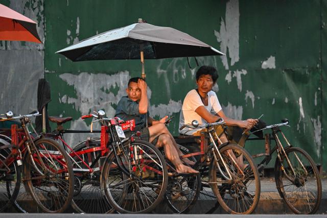 Trishaw drivers wait for customers in Yangon on December 27, 2025, a day before the start of Myanmar's general election. (Photo by NHAC NGUYEN / AFP)
