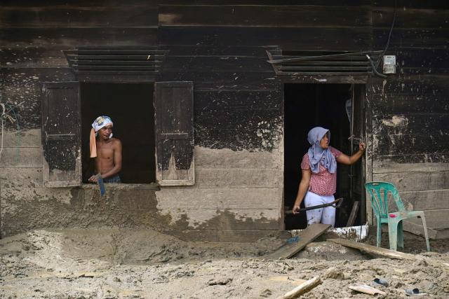 Two villagers clean their home that was damaged by flash floods in Aek Garoga Village, South Tapanuli, North Sumatra, on December 27, 2025. (Photo by YT Hariono / AFP)