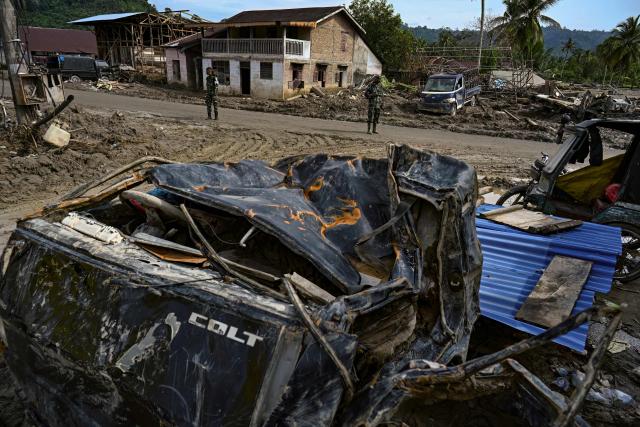 Two members of the Indonesian National Armed Forces assist in the environmental recovery of a residential area affected by flash floods in Aek Garoga Village, South Tapanuli, on December 27, 2025. (Photo by YT Hariono / AFP)