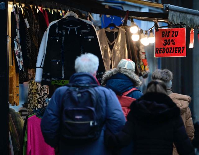 Shoppers walk past a store offering special discounts at a Berlin shopping street on December 27, 2025. (Photo by Tobias SCHWARZ / AFP)