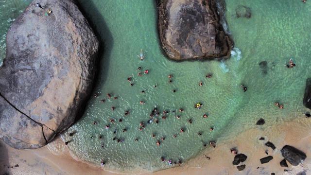 An aerial view shows people enjoying Grumari Beach, located in southwest Rio de Janeiro, Brazil, on December 27, 2025. (Photo by TERCIO TEIXEIRA / AFP)