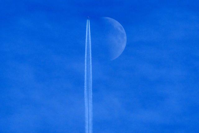 A Boeing 737 Max 8-200 aircraft of Irish budget airline Ryanair flies past the Waxing crescent moon in Frankfurt am Main, western Germany on December 27, 2025. (Photo by Kirill KUDRYAVTSEV / AFP)