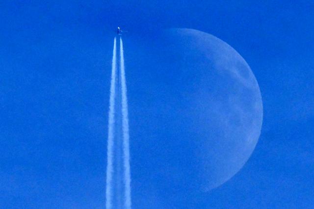 A Boeing 737 Max 8-200 aircraft of Irish budget airline Ryanair flies past the Waxing crescent moon in Frankfurt am Main, western Germany on December 27, 2025. (Photo by Kirill KUDRYAVTSEV / AFP) / ALTERNATIVE CROP